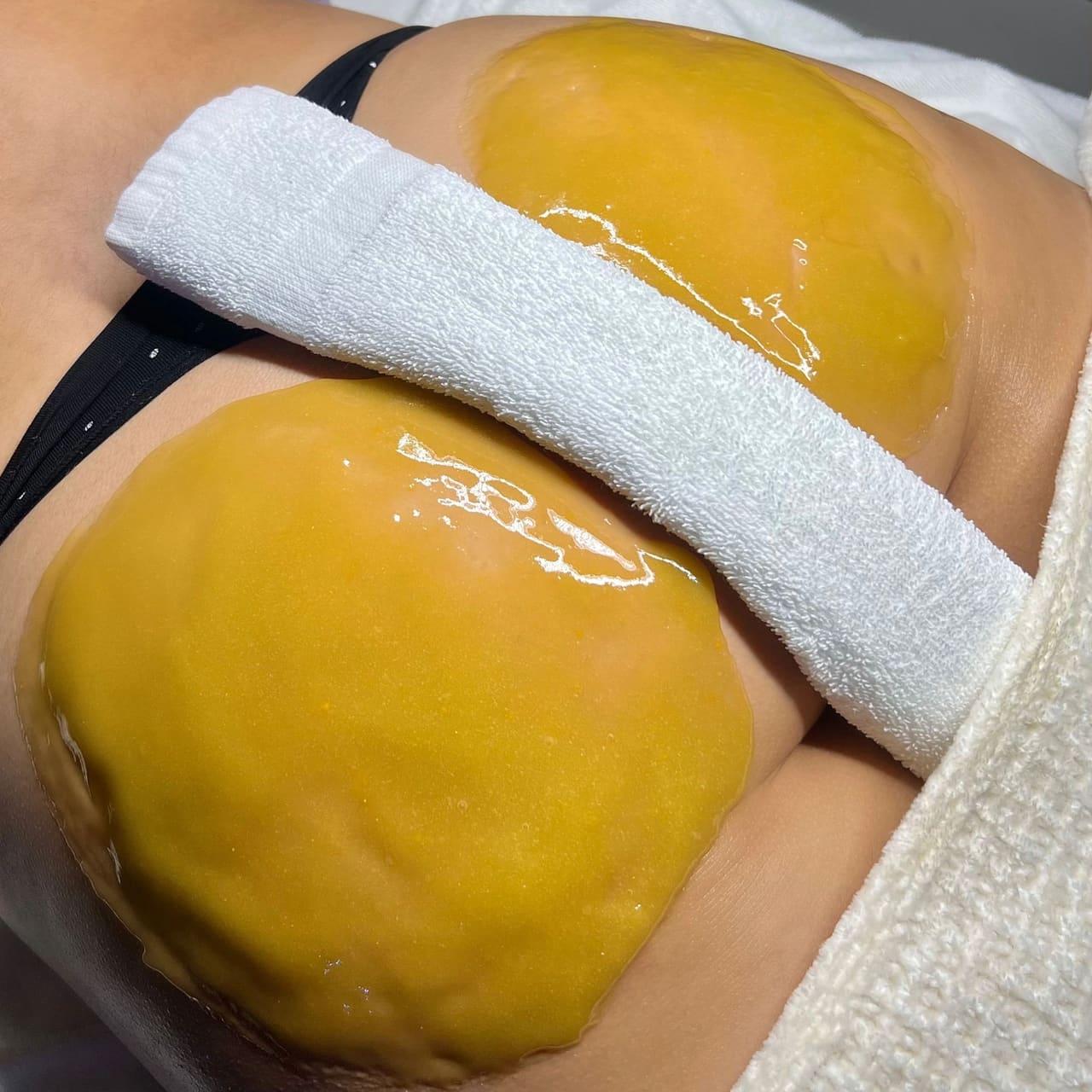 A warm peach-toned exfoliating mask applied during a body facial treatment