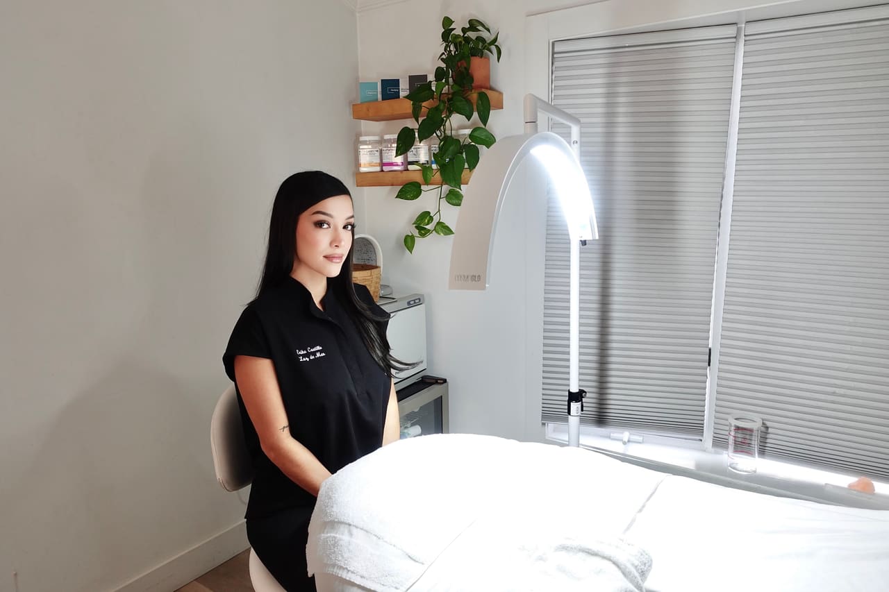 Erika Castillo, licensed aesthetician, beside the treatment bed and LED lamp in her Hampton Bays studio