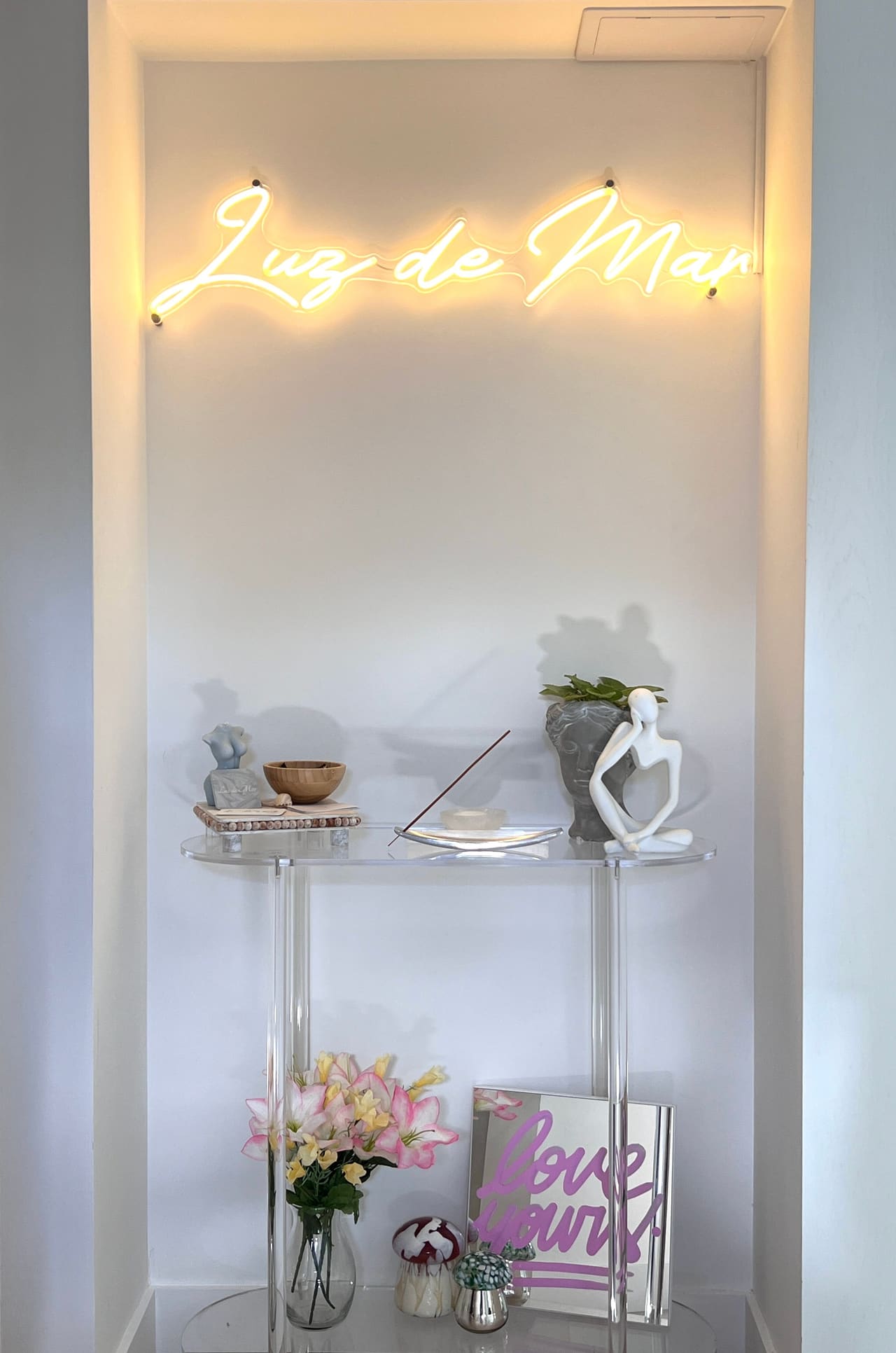 The gold neon Luz de Mar sign glowing above the reception console at the Hampton Bays studio